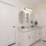 Remodeled primary bathroom vanity with painted cabinets, quartz countertop, double sinks, and updated lighting.